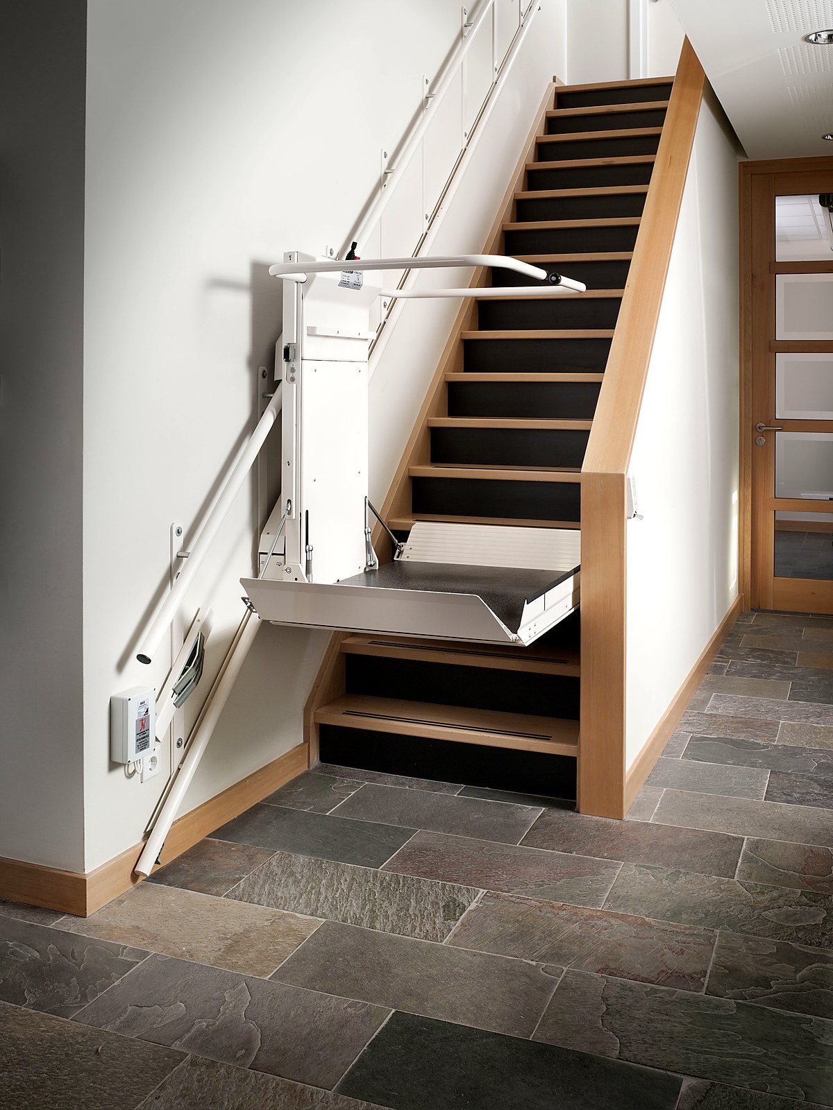 Plattformlift DELTA mit ausgeklappter Plattform an einer geraden Holztreppe